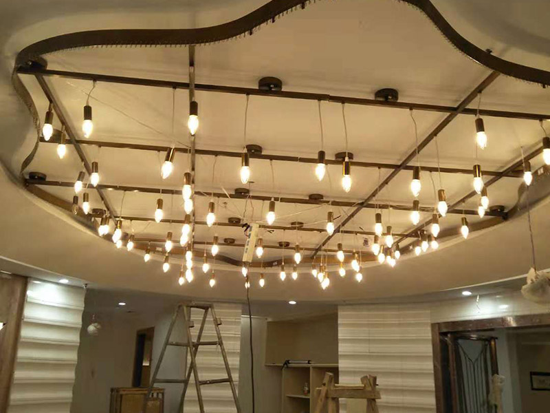 大型吊燈安裝：首先大致尺寸要測量好，確定位置；然后石膏板上鉆孔，然后埋設(shè)鐵件五金配件或者木條，用黏貼劑或者水泥漿將空洞的周邊補齊，等到差不多干燥了再接下來做。接著把鐵件或者木條固定，這是吊燈安裝的重要步驟，如果沒有固定好，使用壽命會受到影響。電線通過吊桿引入到燈芯里面，如果配套燈帶使用開關(guān)的，穿線的時候要注意線路的走向。最后就是燈罩、燈臂的安裝。用看、螺絲刀等工具將燈罩組裝好，安裝好后，通電試試就可以了，根據(jù)實際情況稍微調(diào)整下。