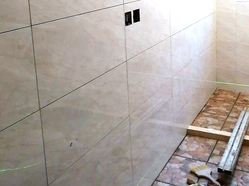 衛(wèi)生間瓷磚鋪貼：基層處理：首先應(yīng)除去基層表面的污垢，油漬，浮灰;除去基層上所有涂料層，膩?zhàn)訉?如果基層未能達(dá)到平整度要求，需對(duì)基層進(jìn)行預(yù)先的找平處理。  放樣：鋪貼瓷磚前需事先找好垂直線，以此為基準(zhǔn)鋪貼的瓷磚高低均勻、垂直美觀;此外，施工前在墻體四周需彈出標(biāo)高控制線，在地面彈出十字線，以控制地磚分隔尺寸。  預(yù)鋪：首先應(yīng)對(duì)瓷磚的色彩、紋理、表面平整等進(jìn)行嚴(yán)格的挑選，然后按照?qǐng)D紙要求預(yù)鋪。 調(diào)制粘結(jié)劑：加水后將粘結(jié)劑漿料攪拌至潤(rùn)滑均勻，無(wú)明顯塊狀或糊狀結(jié)塊，攪拌后的漿料靜置5-10分鐘后再稍加攪拌1-2分鐘即可使用。在開(kāi)始鋪貼施工前，需要先清理瓷磚表面的浮灰，污垢等。  抹漿料：將調(diào)制好的漿料均勻地抹在瓷磚背面，要求漿料飽滿。將瓷磚平整地鋪貼在基層上，使用橡膠錘將瓷磚拍實(shí)鋪平。施工過(guò)程中，可小幅度轉(zhuǎn)動(dòng)瓷磚，使?jié){料與瓷磚背面充分接觸。 瓷磚鋪貼結(jié)束后24小時(shí)，可進(jìn)行嵌縫施工。將調(diào)制好的嵌縫劑均勻地涂在磚與磚的縫隙內(nèi)。嵌縫后用浸濕的織物清理多余的嵌縫劑，保持瓷磚表面清潔。