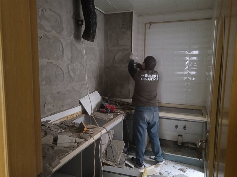 廚房瓷磚拆除：墻面上應(yīng)該還有些其他東西，比如掛毛巾的架子，放廚具的架子等等。先把這些物品都小心翼翼的拆下來，還原一面光潔的墻面，才好進(jìn)行拆卸工作。拆卸的時候要先從墻低的第一塊磚開始拆卸，要是直接隨便從上面那一塊拆卸，拆到一半就會擋住下面的瓷磚，讓下面的瓷磚不好拆了。先用垂子敲最下面的那塊磚，把瓷磚敲松動。送動后，再用戴了手套的手把瓷磚拿下來，小心碎了瓷磚不要劃到手了。拆卸下來的瓷磚堆積在地上很不方便繼續(xù)工作，這個時候上面提到的推車就派上用場了。用推車把瓷磚運走，清理干凈現(xiàn)場，然后繼續(xù)拆卸，直到整面的墻面都拆卸完整。