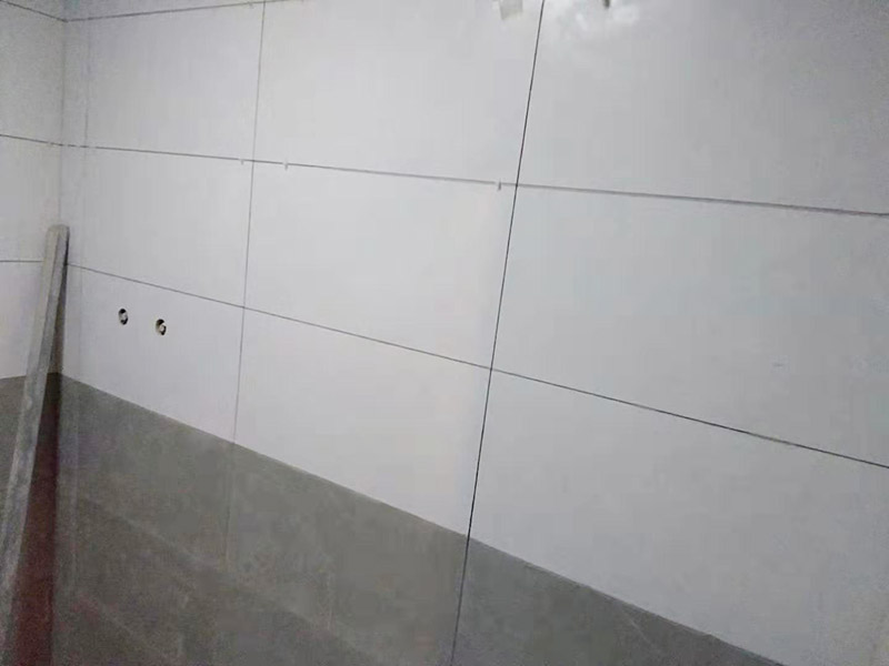 浴室墻面貼瓷磚：貼瓷磚之前先要用水浸泡瓷磚2小時左右。泡水的目的是為了讓瓷磚能事先吸飽水分，避免鋪貼之后吸走粘接材料中的水分，從而影響粘接的強(qiáng)度，浸水后記得用棉布擦去表面的水分晾干后才能進(jìn)行鋪貼。鋪貼開始前還應(yīng)吊垂線，來確定瓷磚的尺寸線，然后開始貼瓷磚，一般都是從門窗先開始，而且按由下而上，自左至右的順序進(jìn)行。鋪貼的方法是先用水潤濕找平層，然后用鏟子將事先拌好的粘接材料抹在瓷磚背面，再將瓷磚貼在墻上即可，依次鋪貼平整就可以了。