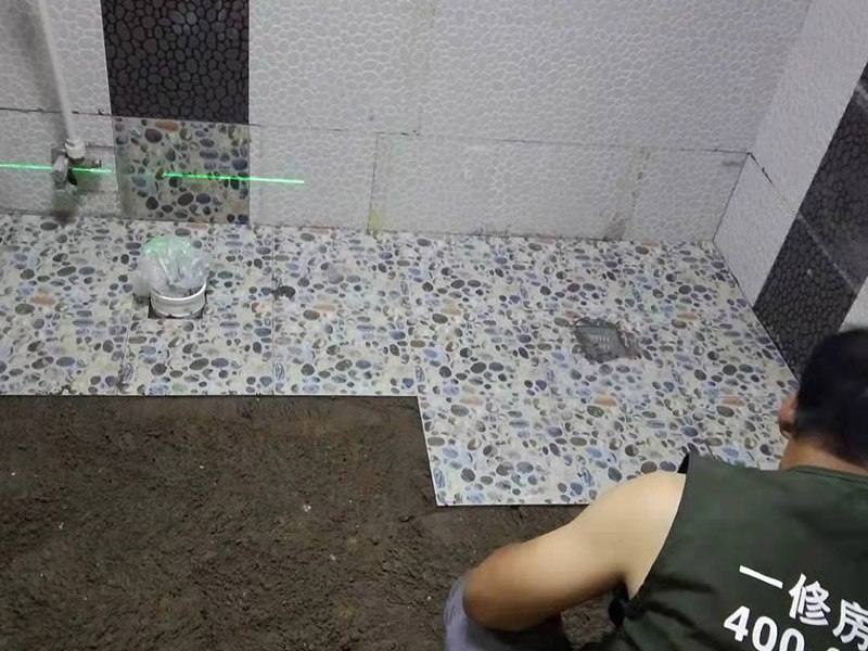 衛(wèi)生間地面花磚鋪貼:找平，就是在鋪仿古磚前，對鋪貼物表面進行處理，如地面、內(nèi)墻面、外墻面等，消除表面附著的污物，并灑水進行滋潤，然后用水泥沙混合找平，通常使用灰鏟在表面不停的涂抹使水泥地面保持大致水平，一定要等到水泥沙混合物完全干爽后再行鋪貼。用一段較長的細線，根據(jù)確定的鋪貼方式，在線上涂上顏色或白灰，然后在找平的地面上畫出仿古磚的位置及磚縫的參考線。 將亞光磚置入清水中浸泡，使瓷磚充分吸收水分，以不冒出氣泡為準，防止干燥瓷磚在裝修完成后再次吸水而導致磚體變形。取出浸泡好的瓷磚，抹干水漬，在找平層上噴灑足夠的水，然后在磚背面均勻抹上水泥沙漿，沙漿厚度5~6cm為宜，鋪貼大規(guī)格亞光磚時適當加厚；隨即將磚貼上，用木錘輕輕拍牢平整，避免空鼓，并隨時用直尺找平。