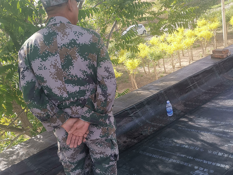 屋頂防水卷材鋪貼:清除基層表面雜物、油污、砂子，凸出表面的石子、砂漿疙瘩等應(yīng)清理干凈，清掃工作必須在施工中隨時進(jìn)行，并修補(bǔ)平整表面。尤其鏟除排水口、煙囪、管壁上的水泥砂漿等附著物；根據(jù)施工現(xiàn)場狀況，進(jìn)行合理定位，確定卷材鋪貼方向，在基層上彈好卷材控制線，依循流水方向從低往高進(jìn)行卷材試鋪。卷材試鋪后，先將要鋪貼的卷材剪好，反鋪于基面上(即是底部隔離紙朝上)，撕剝?nèi)ゾ聿母綦x紙。撕剝時，已剝開的隔離紙宜與粘結(jié)面保持45～60度的銳角，防止拉斷隔離紙，盡量保持在自然松弛狀態(tài)，但不要有皺折。