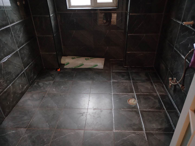 衛(wèi)生間美縫施工：使用用開槽器/平口螺絲刀/勾縫刀，清理瓷磚縫隙內(nèi)灰塵及垃圾，這一步需要力度適中，不要用蠻力，不然可能存在崩壞瓷磚的風(fēng)險(xiǎn)。然后用吸塵器，掃把或者抹布清理干凈。，建議縫隙在1.5到2mm深度合適。縫隙清理干凈后， 擰開管蓋裝上混合管，管頭卡在膠槍的卡口上。裝好混合管后，從下方用美工刀斜切45度角，切記開口要比瓷磚縫隙小，如果本身瓷磚縫隙比較小，可以不用切膠嘴。首先打出30-40CM美縫劑余料，然后沿著瓷磚縫隙開始施工，在施工的時(shí)候一定要美縫劑填充滿瓷磚縫隙，不然后續(xù)可能會(huì)發(fā)生塌陷。瓷磚縫隙打膠方法先豎后橫，沿著縫隙均勻打出美縫劑.一般有些師傅打出3-5米時(shí)停下，開始用壓邊球壓縫，十字交叉口處多壓幾次，這樣會(huì)很美觀。壓縫的工具比較多，可用刮板或者壓縫 鋼球、手指套沿著縫隙壓出 U型面就可以了