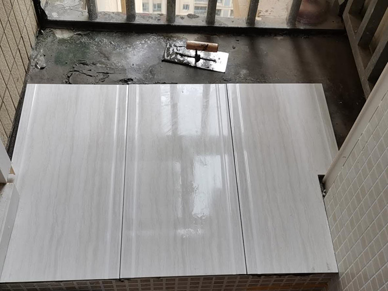 陽臺(tái)瓷磚鋪貼：準(zhǔn)備粘結(jié)劑前，瓷磚不應(yīng)浸水，但要用鋼絲刷除去磚背面的松散物質(zhì)，并用濕布抹去磚背的浮塵。然后按照生產(chǎn)商建議的比例將水或乳液放到攪拌桶中攪拌直至粘結(jié)劑均勻無結(jié)塊。初始攪拌后的粘結(jié)劑應(yīng)靜置在攪拌桶中，直到生產(chǎn)商推薦的熟化時(shí)間過后攪拌一下再使用。 在鋪壓瓷磚前，在瓷磚背面也批一薄層粘結(jié)劑。這種雙批法雖然用的材料和工時(shí)比較多，但卻能夠保證粘貼的質(zhì)量和耐久性。 在粘結(jié)劑量置晾時(shí)間內(nèi)，將準(zhǔn)備好的瓷磚鋪壓到位，垂直于梳理方向輕微搓動(dòng)以排出磚下的空氣。鋪貼到位后用橡皮錘輕擊，用尺寸合適的十字定位架來調(diào)整表面平整度及接縫的平直。