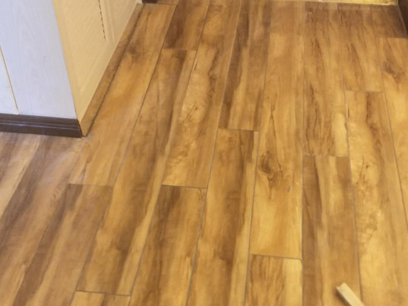 入戶門鋪地板：1、先對地面進(jìn)行找平，水平的誤差不能超過2毫米。地面要是不平，腳感就不好。再就是將邊、角部位等突起或有不平的地方進(jìn)行局部修整。再鋪防潮層，防潮層可以防止以后地板受潮。鋪平，接縫處要并攏。  2、然后就是安裝地板了，因為地板是要錯落安裝的，先預(yù)鋪一下，將部分地板一分為二，要按尺寸來鋸，萬一鋸多了，地板損耗就大了。因為地板有一定的膨脹率，因此鋪裝前要在其與墻面接觸的部位預(yù)留膨脹縫，以免地板起鼓。膨脹縫的大小一般和地板的膨脹系數(shù)有關(guān)系。粘合地板的膠水要用強(qiáng)化地板專用的，這種膠的污染比較小。不要隨便在市場上選非地板專用膠，地板本身就存在的污染上再增加污染源。  3、鋪前看好地板是否用對，再鋪設(shè)地板。在鋪設(shè)時，要一塊短的旁邊鋪一塊長的，這樣交叉鋪設(shè)地板就咬得住不易松動，地板拼合后還要用工具敲緊。再下來就是銜接了，一般用地板壓條掩蓋。但也有用玻璃膠填充。