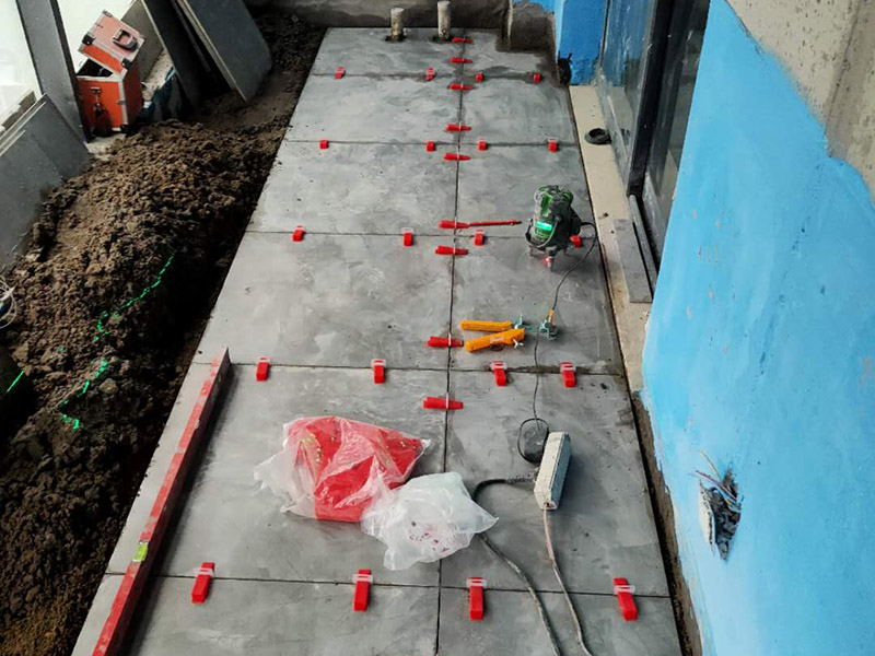 陽臺(tái)防水貼磚:在粘結(jié)劑量置晾時(shí)間內(nèi)，將準(zhǔn)備好的瓷磚鋪壓到位，垂直于梳理方向輕微搓動(dòng)以排出磚下的空氣。鋪貼到位后用橡皮錘輕擊，用尺寸合適的十字定位架來調(diào)整表面平整度及接縫的平直。鋪設(shè)好的磚面應(yīng)該及時(shí)清理干凈，特別是去除殘留其上的粘結(jié)劑。合格的粘結(jié)劑干硬后即使在陶瓷磚面上也不易被清除掉。清理好的瓷磚面應(yīng)該立即擺放標(biāo)識進(jìn)行隔離，避免污染或擾動(dòng)，直到下一個(gè)填縫工序。