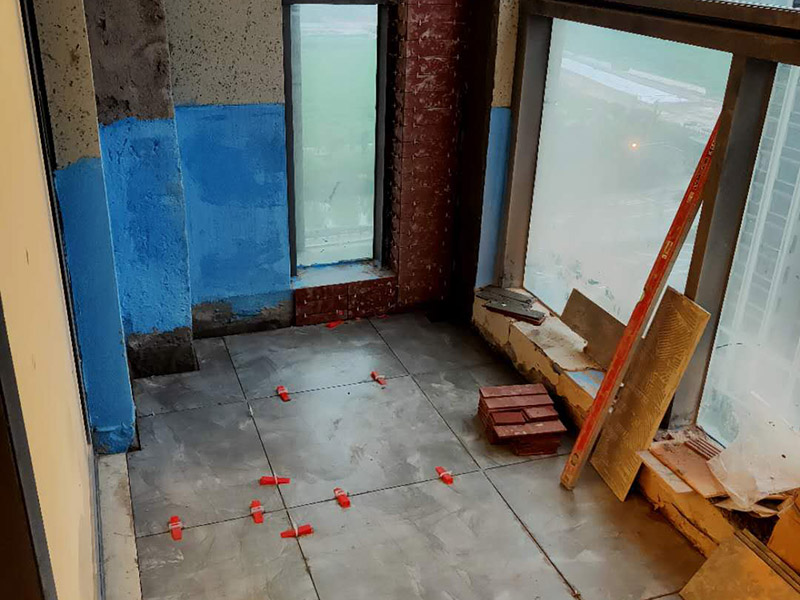 陽臺(tái)防水貼磚:在粘結(jié)劑量置晾時(shí)間內(nèi)，將準(zhǔn)備好的瓷磚鋪壓到位，垂直于梳理方向輕微搓動(dòng)以排出磚下的空氣。鋪貼到位后用橡皮錘輕擊，用尺寸合適的十字定位架來調(diào)整表面平整度及接縫的平直。鋪設(shè)好的磚面應(yīng)該及時(shí)清理干凈，特別是去除殘留其上的粘結(jié)劑。合格的粘結(jié)劑干硬后即使在陶瓷磚面上也不易被清除掉。清理好的瓷磚面應(yīng)該立即擺放標(biāo)識進(jìn)行隔離，避免污染或擾動(dòng)，直到下一個(gè)填縫工序。