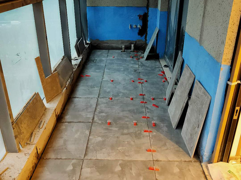 陽臺(tái)防水貼磚:在粘結(jié)劑量置晾時(shí)間內(nèi)，將準(zhǔn)備好的瓷磚鋪壓到位，垂直于梳理方向輕微搓動(dòng)以排出磚下的空氣。鋪貼到位后用橡皮錘輕擊，用尺寸合適的十字定位架來調(diào)整表面平整度及接縫的平直。鋪設(shè)好的磚面應(yīng)該及時(shí)清理干凈，特別是去除殘留其上的粘結(jié)劑。合格的粘結(jié)劑干硬后即使在陶瓷磚面上也不易被清除掉。清理好的瓷磚面應(yīng)該立即擺放標(biāo)識進(jìn)行隔離，避免污染或擾動(dòng)，直到下一個(gè)填縫工序。