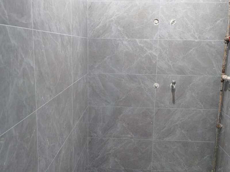 衛(wèi)生間貼磚施工：應(yīng)全部清理墻面上的各類污物，打掃干凈現(xiàn)場，特別是腳落里。用泥刀先批墻，后用水泥漿找平。這個工序很重要，確保底子平，防止貼后空鼓。墻面要刷防水涂料，防止貼后浸水，一般高度不低于1.8米，刷的時候會稍高一些。根據(jù)設(shè)計鋪貼圖樣的要求，確定排磚方案，用墨斗彈線，以減少施工損耗。把剛剛攪拌好的粘結(jié)劑漿料均勻的刮到墻上。瓷磚上墻將經(jīng)過預(yù)先清潔的瓷磚平整地鋪貼在粘結(jié)劑漿料基層上，使用橡膠錘將瓷磚拍實鋪平。施工過程中，可小幅度轉(zhuǎn)動瓷磚，使?jié){料與瓷磚背面充分接觸。專家建議在鋪貼時，隨機取下已鋪貼于基層上的瓷磚作檢查。確保漿料與瓷磚背面的充分接觸。 留縫大小調(diào)整根據(jù)瓷磚的尺寸，在磚與磚之間預(yù)留相應(yīng)尺寸的縫隙留待嵌縫。可用牙簽等先固定，粘結(jié)劑具有一定的可調(diào)整性，可對留縫的大小進(jìn)行調(diào)整。