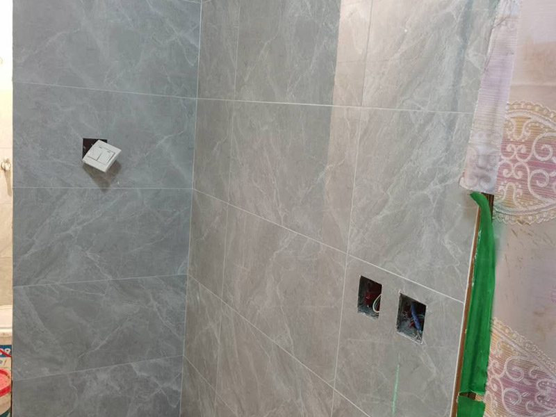 衛(wèi)生間貼磚施工：應(yīng)全部清理墻面上的各類污物，打掃干凈現(xiàn)場，特別是腳落里。用泥刀先批墻，后用水泥漿找平。這個工序很重要，確保底子平，防止貼后空鼓。墻面要刷防水涂料，防止貼后浸水，一般高度不低于1.8米，刷的時候會稍高一些。根據(jù)設(shè)計鋪貼圖樣的要求，確定排磚方案，用墨斗彈線，以減少施工損耗。把剛剛攪拌好的粘結(jié)劑漿料均勻的刮到墻上。瓷磚上墻將經(jīng)過預(yù)先清潔的瓷磚平整地鋪貼在粘結(jié)劑漿料基層上，使用橡膠錘將瓷磚拍實鋪平。施工過程中，可小幅度轉(zhuǎn)動瓷磚，使?jié){料與瓷磚背面充分接觸。專家建議在鋪貼時，隨機取下已鋪貼于基層上的瓷磚作檢查。確保漿料與瓷磚背面的充分接觸。 留縫大小調(diào)整根據(jù)瓷磚的尺寸，在磚與磚之間預(yù)留相應(yīng)尺寸的縫隙留待嵌縫?？捎醚篮灥认裙潭?，粘結(jié)劑具有一定的可調(diào)整性，可對留縫的大小進(jìn)行調(diào)整。