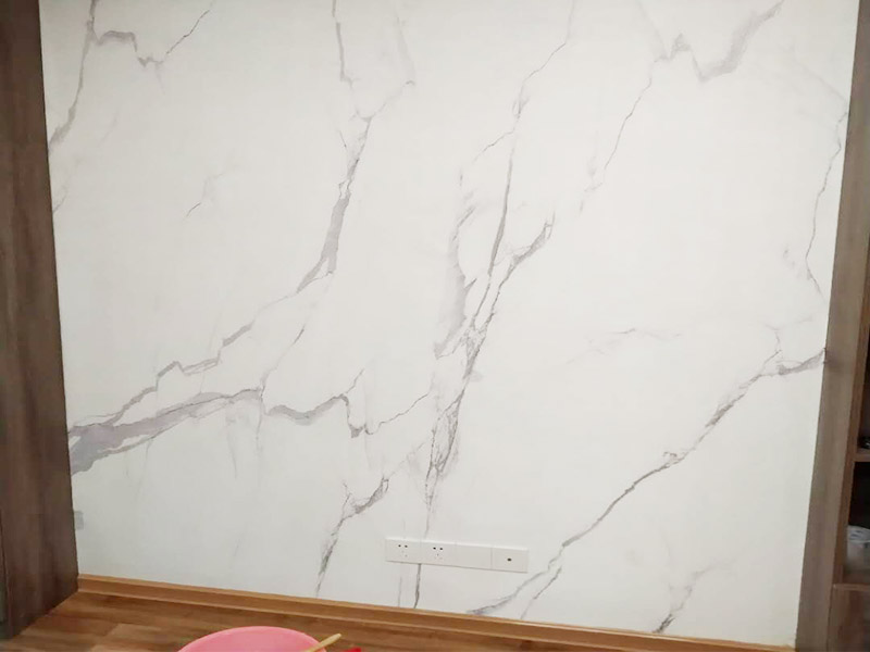 電視背景墻裝修：首先需要量背景墻的尺寸，然后記錄下來，可以去網(wǎng)上或者實體店購買墻布。要注意尺寸要留有余地，才能進行處理。要對貼墻布的墻面先進行處理，墻面如果是剛做好的水泥漆，干了就可以操作。如果是普通的墻面，需要先做基膜。把購買來的墻布展開，然后站到梯椅上，把墻布對角貼上去。要注意張貼的平整，不能一邊高一邊低。用手按壓住墻布，然后用刮片把墻布刮平。刮角落的時候，要注意用力刮平，不要有褶皺或者翹角。墻布刮好后，要用鋒利的刀片，進行修邊處理，電線孔也要用刀片割開。修邊好后，也要用刮片再刮一遍。裁剪邊框的墻紙，按照同樣步驟張貼。張貼好后，用布擦一下，防止膠水沾住。查看張貼效果，關(guān)上窗戶。