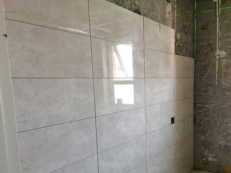 客廳瓷磚鋪貼:鋪貼前，先將所鋪平面表面的塵土、雜物等徹底清掃干凈，平面不能有空鼓、開裂和起砂等現(xiàn)象，如果存在這些現(xiàn)象，要先進(jìn)行修復(fù)處理，在鋪設(shè)瓷磚。鋪設(shè)地磚施工前，要先在地面彈出十字線，從而控制地磚分隔尺寸。然后要選用1:3干硬性水泥砂漿，砂漿的厚度要在25mm左右。把瓷磚按照要求放在水泥砂漿上，用橡皮錘輕輕敲擊瓷磚的表面，直至瓷磚鋪貼平整。鋪貼完瓷磚后，要進(jìn)行勾縫處理，先清理干凈瓷磚縫隙里的雜質(zhì)，再用專用填縫劑進(jìn)行勾縫處理。