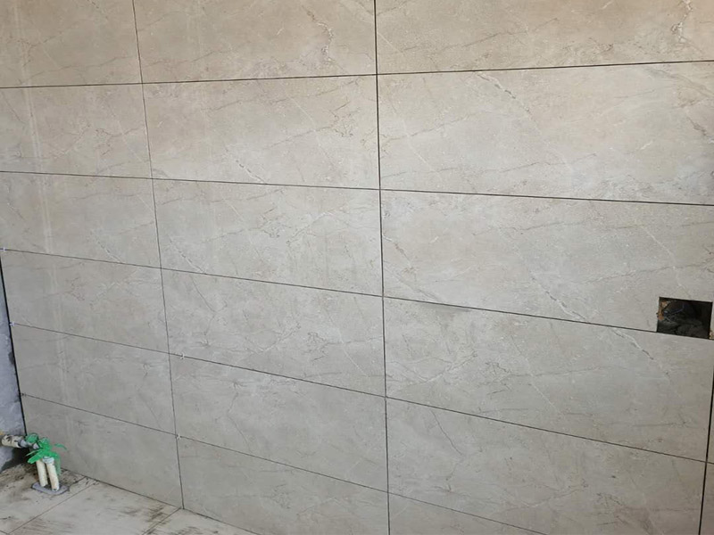 客廳瓷磚鋪貼:鋪貼前，先將所鋪平面表面的塵土、雜物等徹底清掃干凈，平面不能有空鼓、開裂和起砂等現(xiàn)象，如果存在這些現(xiàn)象，要先進(jìn)行修復(fù)處理，在鋪設(shè)瓷磚。鋪設(shè)地磚施工前，要先在地面彈出十字線，從而控制地磚分隔尺寸。然后要選用1:3干硬性水泥砂漿，砂漿的厚度要在25mm左右。把瓷磚按照要求放在水泥砂漿上，用橡皮錘輕輕敲擊瓷磚的表面，直至瓷磚鋪貼平整。鋪貼完瓷磚后，要進(jìn)行勾縫處理，先清理干凈瓷磚縫隙里的雜質(zhì)，再用專用填縫劑進(jìn)行勾縫處理。