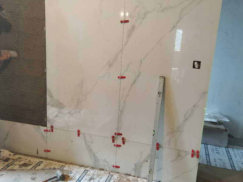 形象墻貼磚案例：將瓷麗貼粉劑倒入清水中攪拌成膏狀（混合比例：20kg粉劑＋6kg清水），攪拌完畢后需靜止放置約10分鐘，再略微攪拌一下才可使用，有助于增加貼結(jié)力。 用齒型刮板將膠漿涂抹于工作面之上，使之均勻分布，并成一條條齒狀。 在晾置時(shí)間內(nèi)將瓷磚揉壓于上即可。