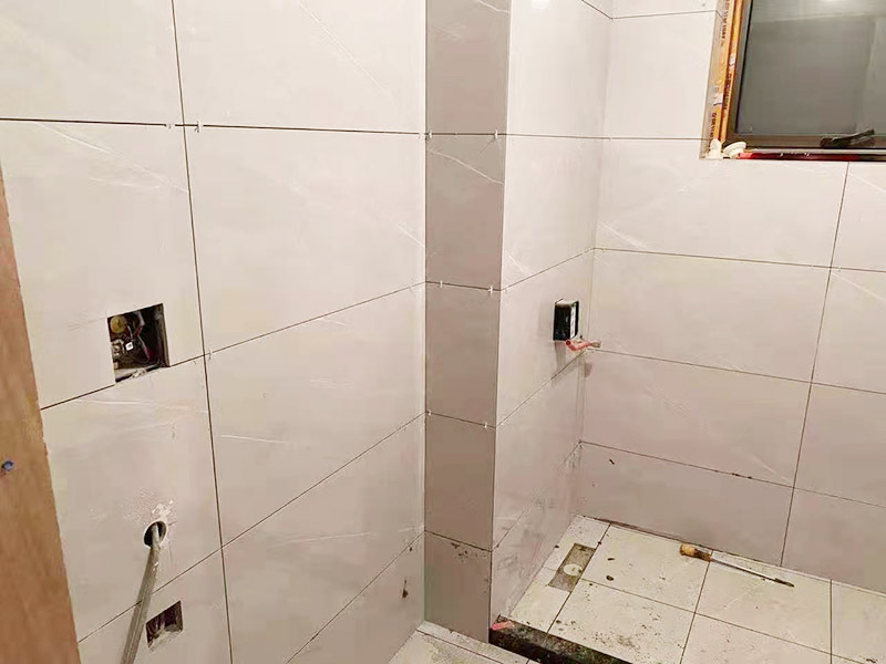 衛(wèi)生間貼磚施工：衛(wèi)生間貼磚要先將所需材料準(zhǔn)備好，一般用在這個(gè)空間的話可以選擇小瓷磚，例如小方塊類型的瓷磚就不錯(cuò)，貼起來也比較方便。然后將水泥與建筑膠混合拌勻，用鏟刀將其鏟到地面刮平再將瓷磚鋪上刀壓實(shí)，這樣按照這樣的方式自上而下或自左而右來進(jìn)行貼磚即可。